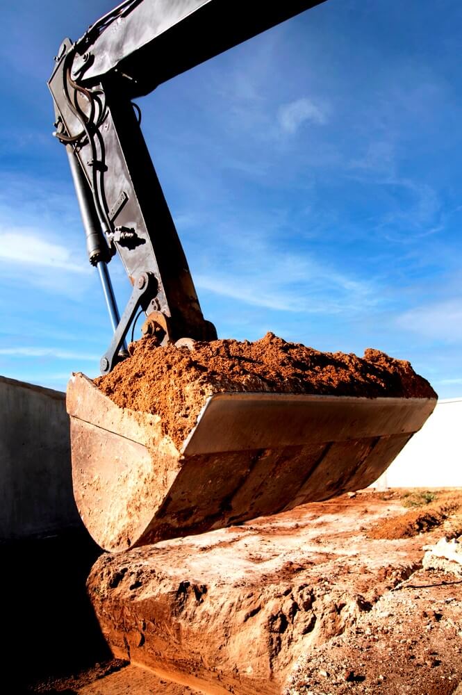 excavatrice qui met de la terre dans un trou